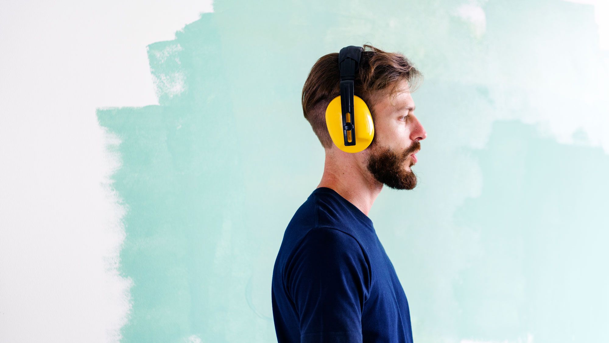 Man renovating his home with earmuffs on